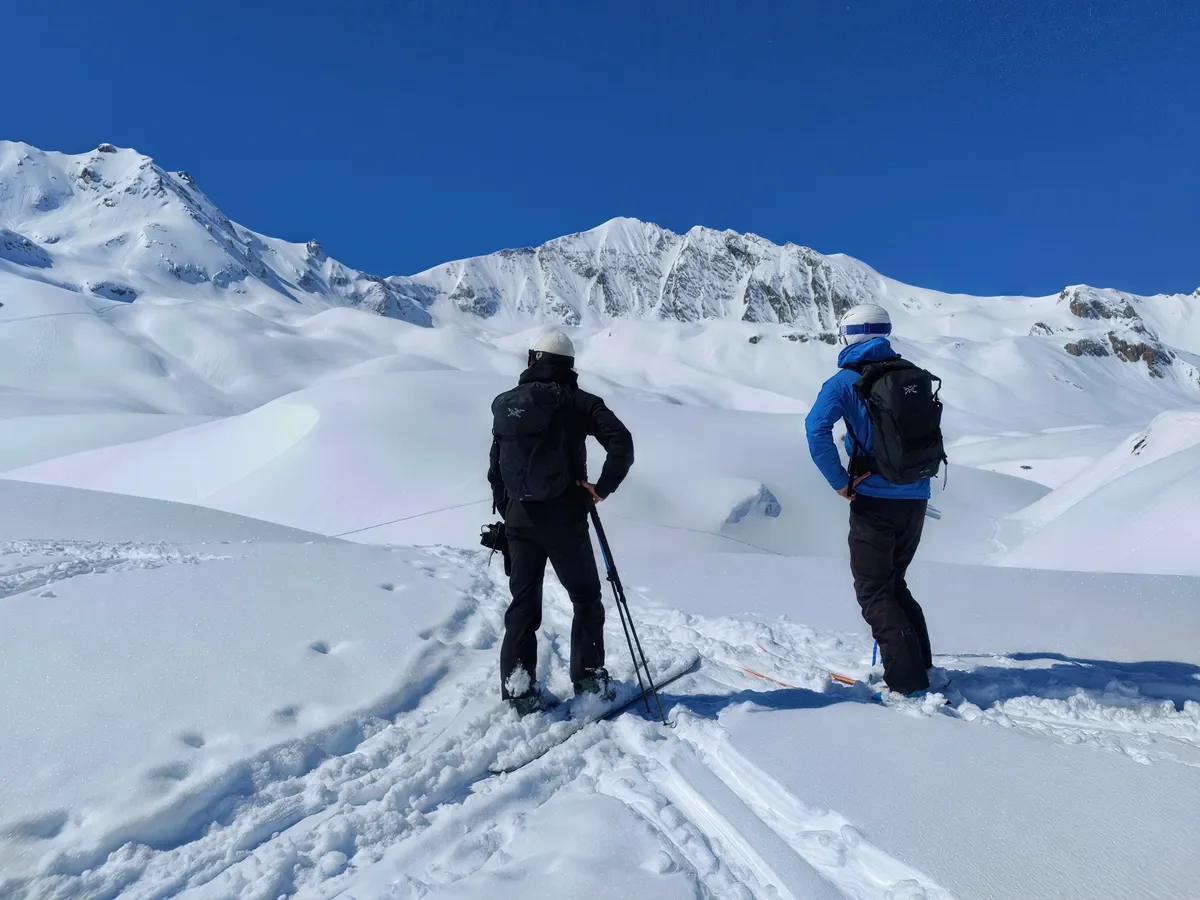 Skieurs en randonnée contemplant les sommets des Alpes et l'immensité du domaine